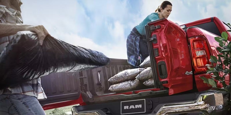 Person loading cargo into the 2026 RAM 1500 truck bed in Springfield, MI